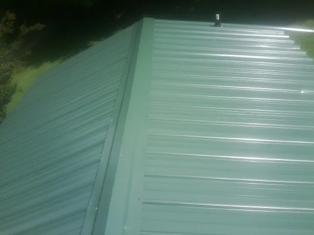 New green metal panels meeting at the ridge of a roof — Flat Roof Repair work by our crew in Chadwick