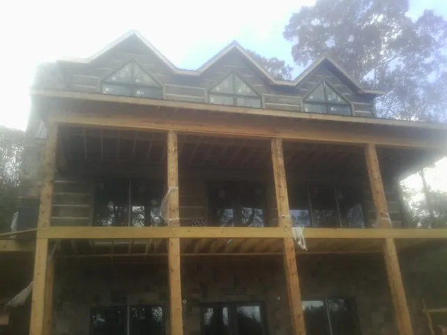 Dormers and porch framing on a large log home under construction — Roof Coating work by our crew in Chadwick