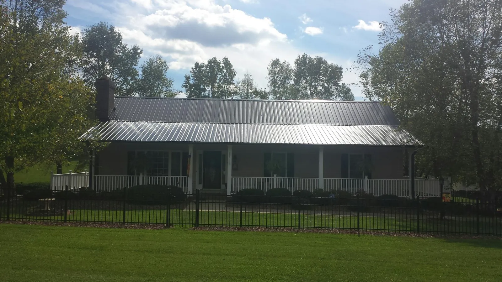 Gray metal roof on a brick ranch with a full width front porch — Gutter Guard Installation work by our crew in Chadwick